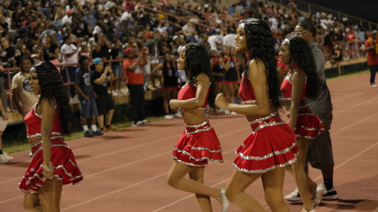 Dancers in red performing in front of full stadium stands at night.