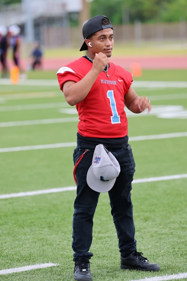 A young man in a red Madison number 1 jersey and backwards cap standing on the field.