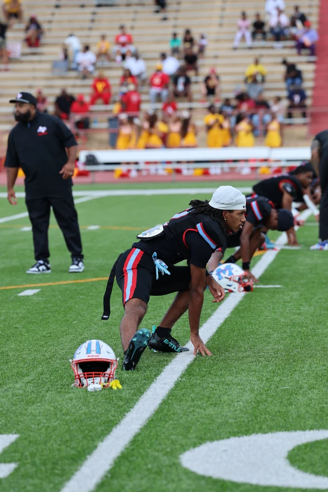 Madison players stretching in a line beside their helmets before the game.